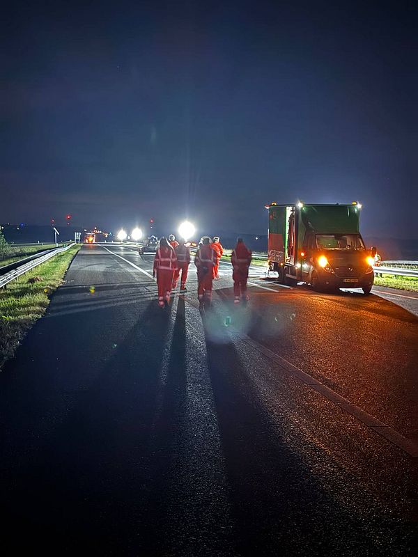 A group of workers in reflective gear conducts a safety walk on a dark road.