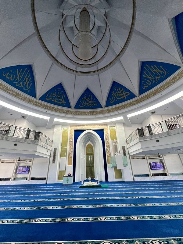 The image captures the interior of a mosque featuring a beautifully designed dome and prayer area.