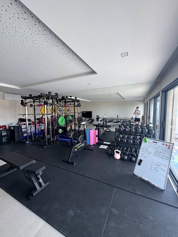 A modern home gym featuring various workout equipment and a whiteboard with notes.