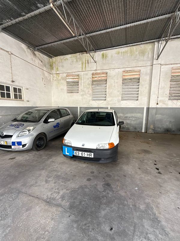 A parking area with two cars, one of which is a driving school vehicle.