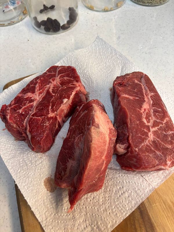 Three pieces of raw steak are displayed on a paper towel.