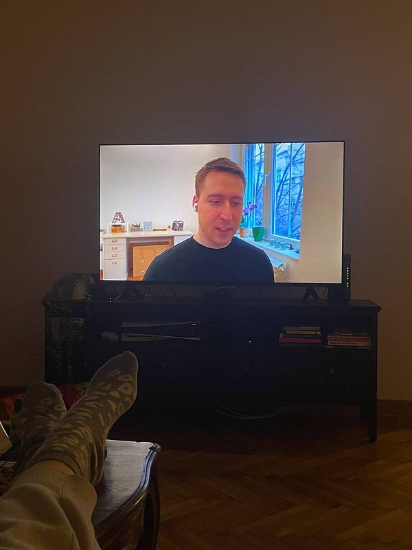 A person is relaxing while watching a podcast on a television.