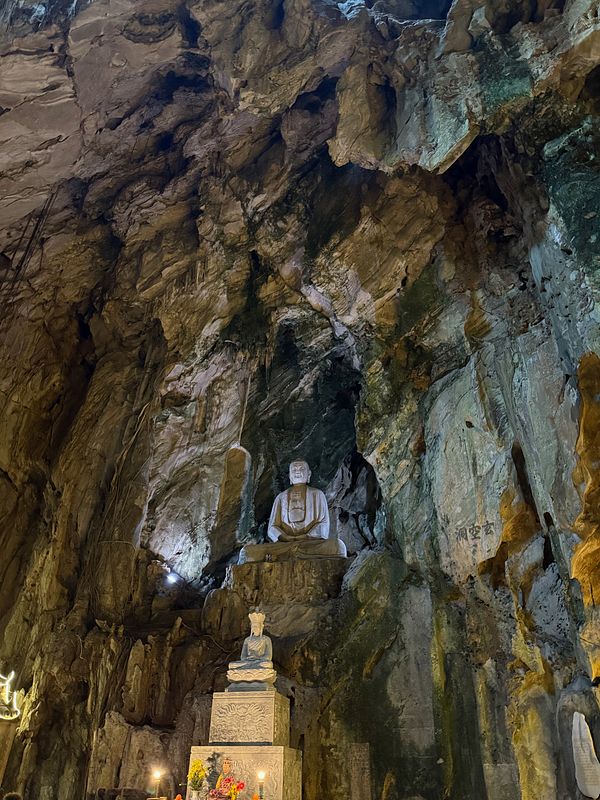A serene cave interior featuring Buddhist statues and natural rock formations.
