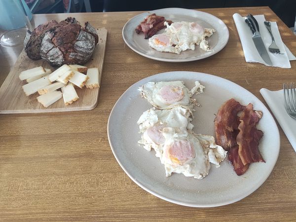 A breakfast spread featuring eggs, bacon, and bread.