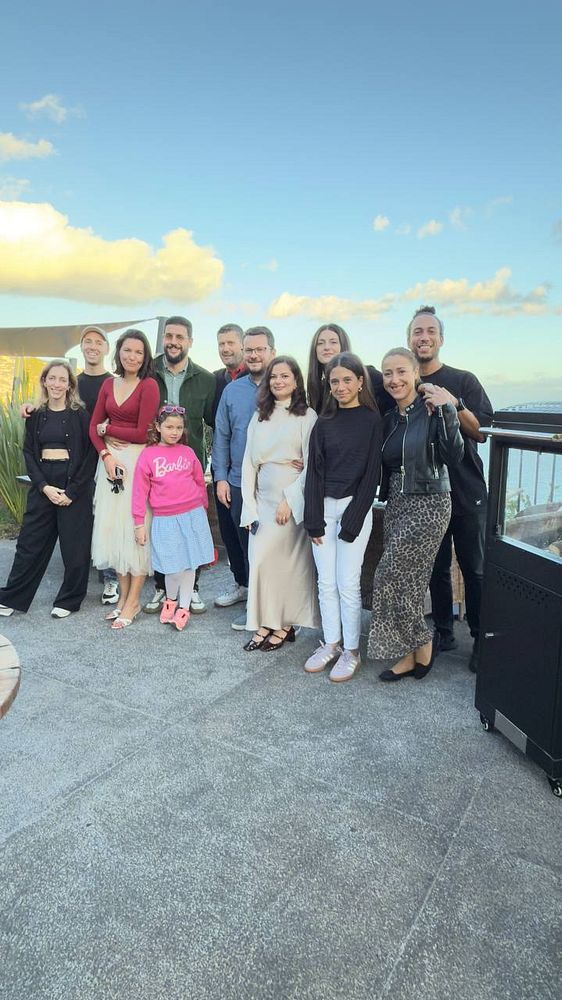 A group of friends poses together for a birthday celebration outdoors.