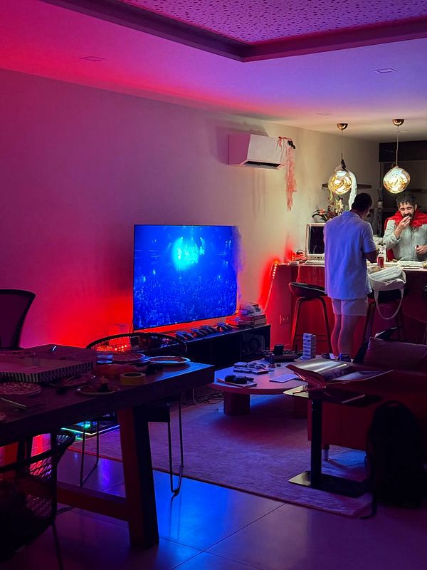 A cozy indoor setting is prepared for a Halloween BBQ party, featuring colorful lighting and a lively atmosphere.