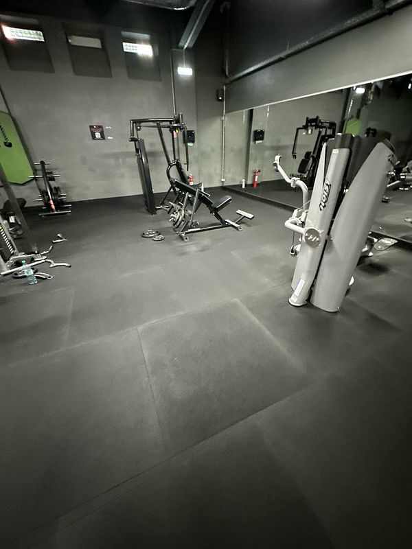 The image depicts a gym interior featuring various exercise equipment.