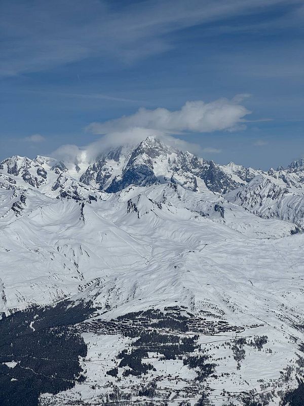A nighttime sky photo featuring a crescent moon and silhouettes of rooftops and antenna against a gradient sky from blue to dark.