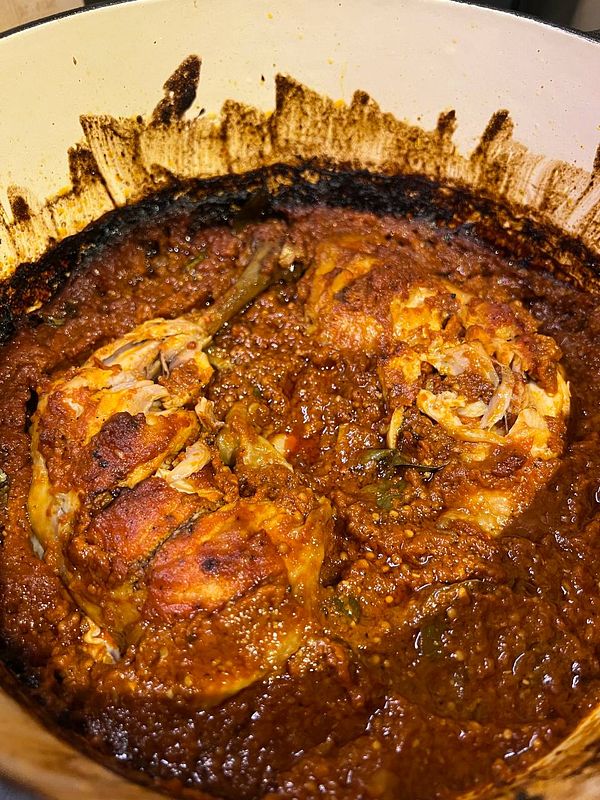 A pot of Goan chicken curry, showcasing rich colors and textures.