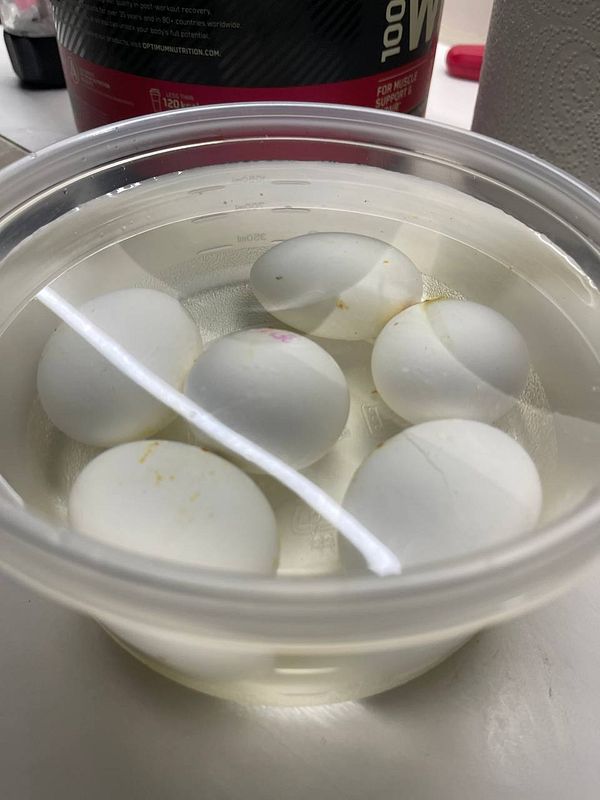 A container filled with eggs submerged in water, preparing for boiling.