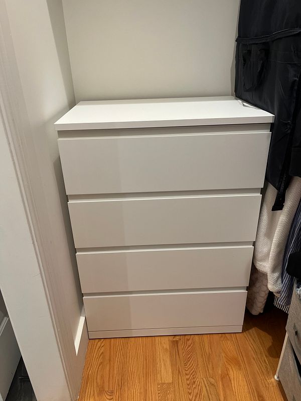 Photo of an instruction manual page showing steps to assemble a piece of furniture with wooden parts and screws.