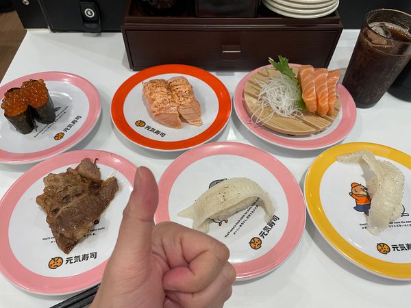 A vibrant city street scene showing a spacious pedestrian area with people walking and a colorful sky.