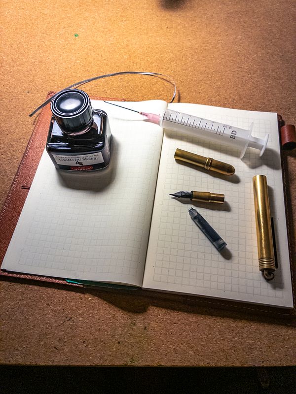 The image features a workspace set up for refilling a TRC pen with ink.