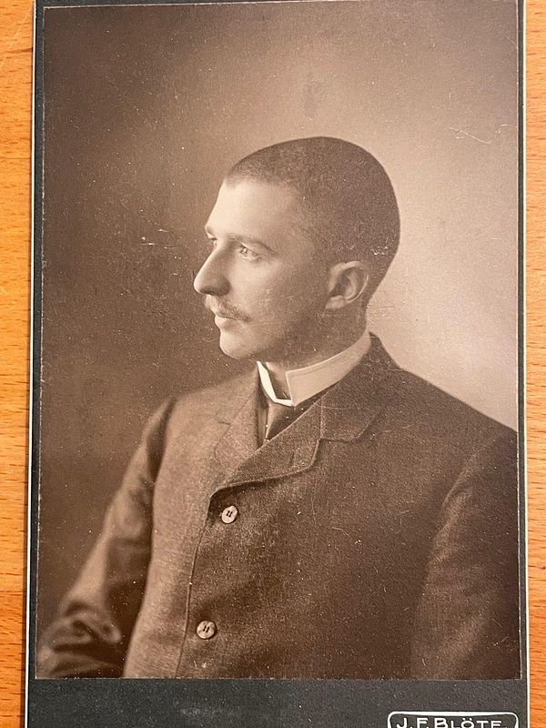 A vintage portrait of a young man in formal attire, captured in profile.