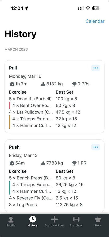 A man training in a gym using gymnastic rings suspended from the ceiling.