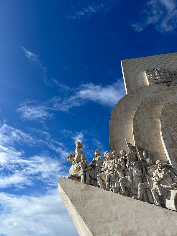 A scenic view of the Belém Tower in Lisbon situated on the Tagus River under a partly cloudy sky.