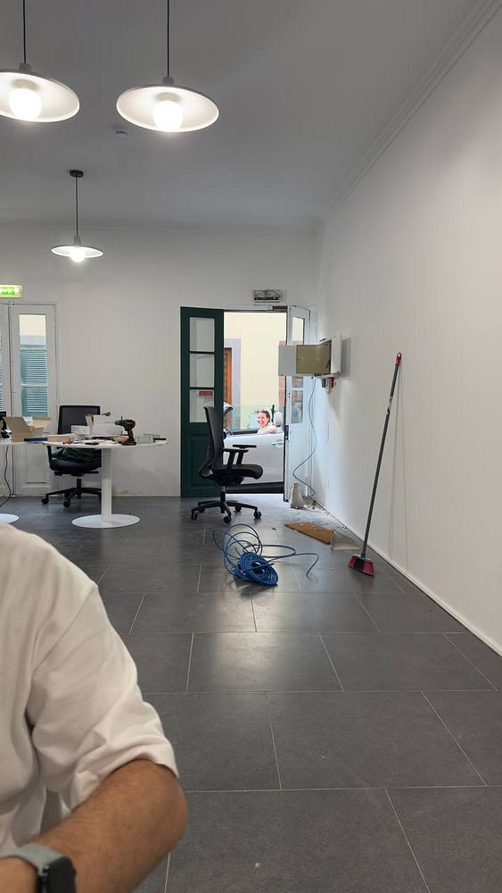 The image depicts an office space under renovation with visible construction elements and furniture.