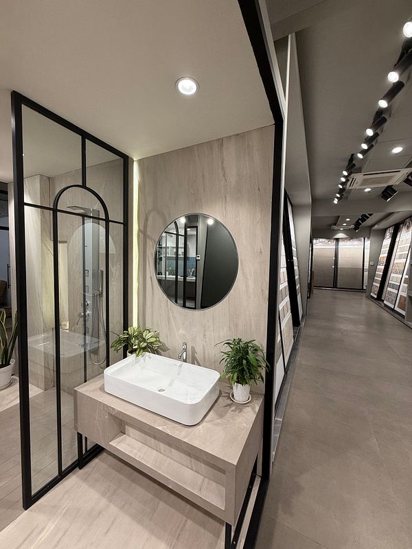A modern bathroom display featuring a sleek sink and shower area in a showroom.