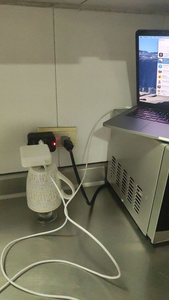 A laptop is connected to a power source using a creative charging setup.
