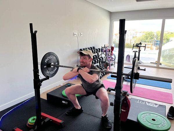 A person is performing a squat with a barbell in a home gym setting.