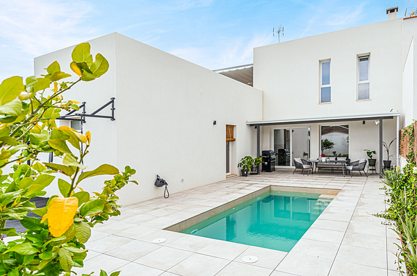 A modern villa with a private pool and outdoor seating area.
