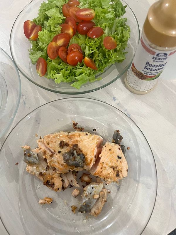 A meal preparation featuring cooked salmon and a fresh salad.