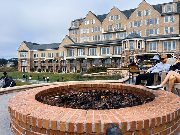 A cozy fire pit is situated in front of a large, elegant building with multiple stories.