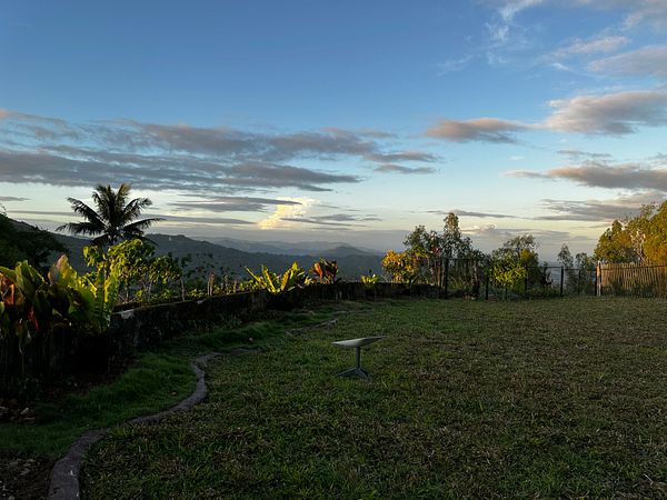 A scenic view of a garden area overlooking a mountainous landscape during sunset.