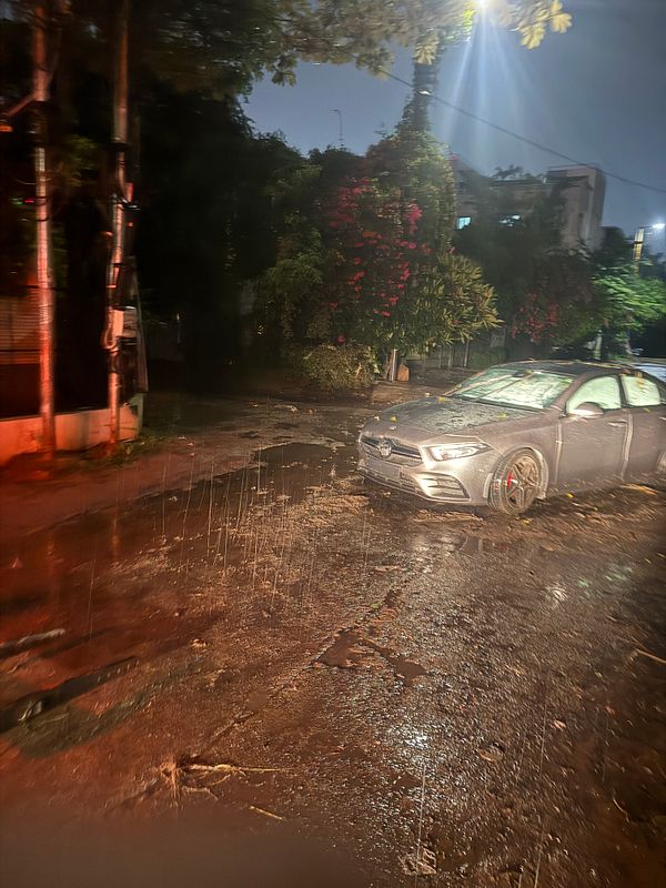 A flooded car is parked on a wet street during a rainstorm.