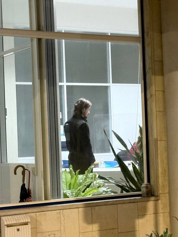 A person stands inside a driving school, visible through a large window.