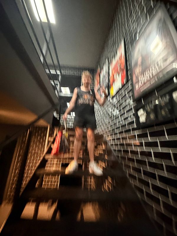 Person in a gym room performing Muay Thai training using punching pads held by a trainer.