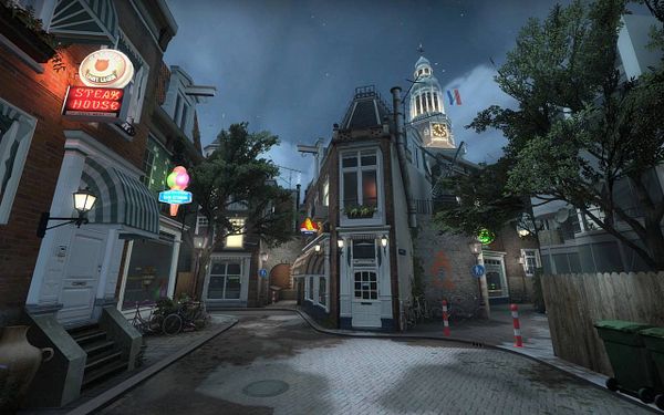 Detailed urban street scene from a video game map set in Amsterdam, featuring narrow buildings, neon signs, and a clock tower with the Dutch flag.