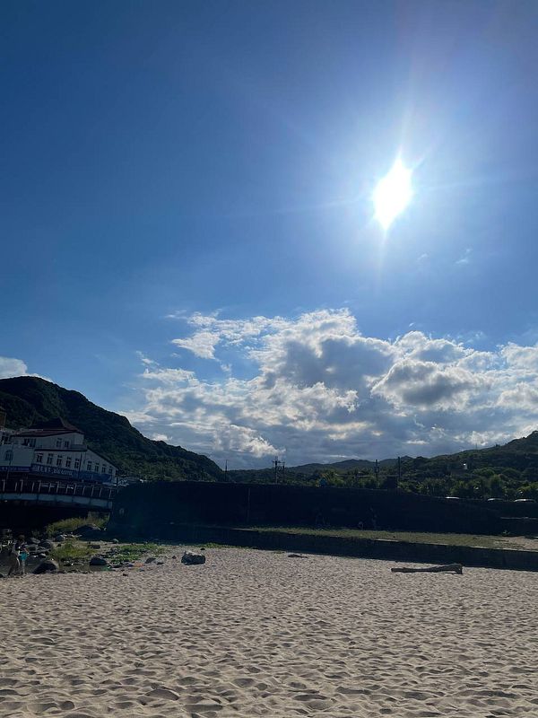 A sunny beach scene with a clear sky and distant mountains.