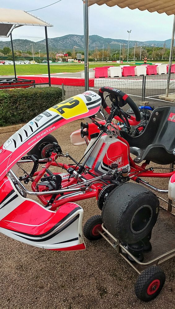 A close-up view of a red and white go-kart parked at a racing track.