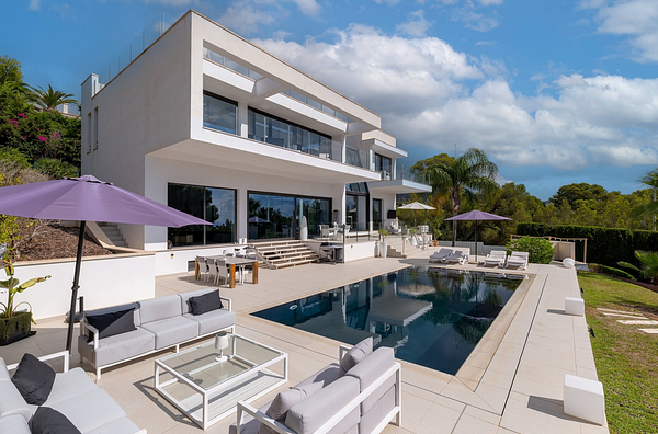 Two luxurious Mediterranean-style villas with lush landscaping and clear skies.