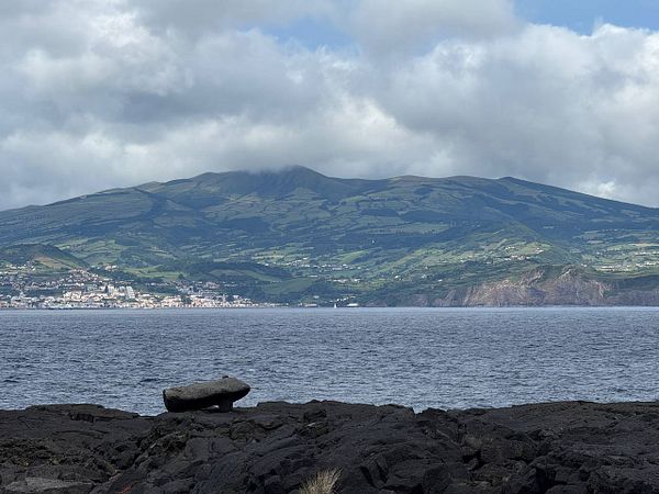 A scenic view of a coastal landscape featuring mountains, a town, and the ocean.