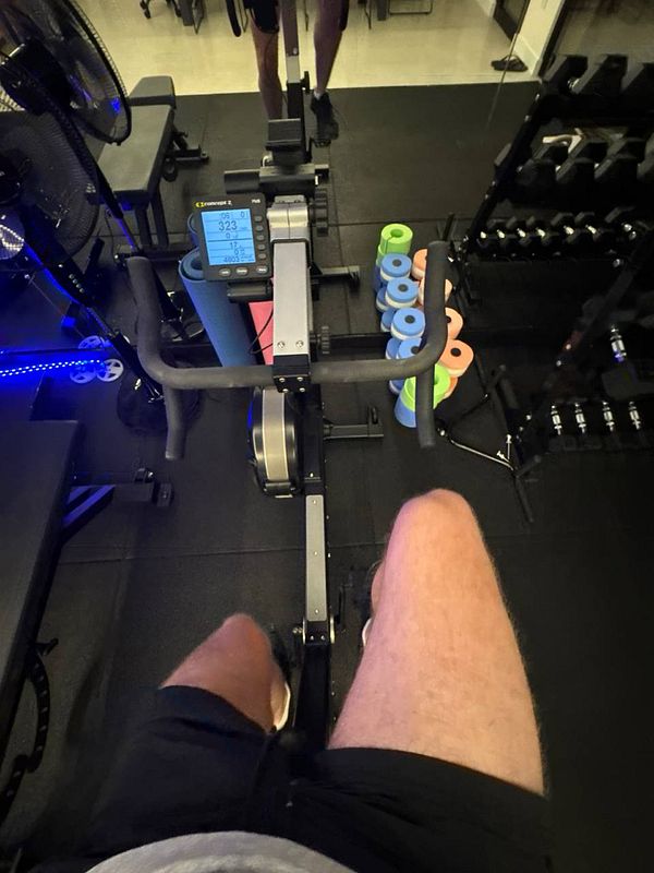 A person is exercising on a rowing machine in a gym setting.