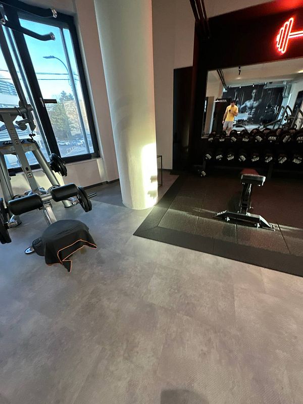 A modern gym interior featuring workout equipment and a large mirror.