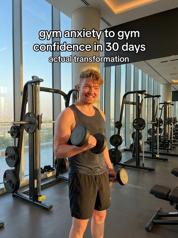 A man is lifting dumbbells in a gym, showcasing a transformation from gym anxiety to confidence.