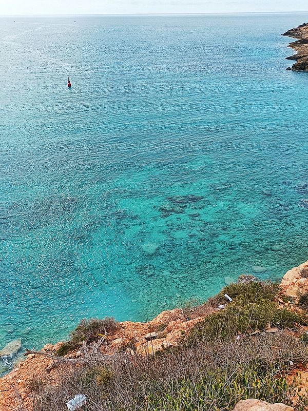 A scenic view of clear turquoise waters along a rocky coastline.