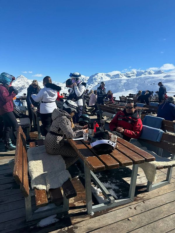 A lively outdoor ski area with people enjoying the sun and snow.