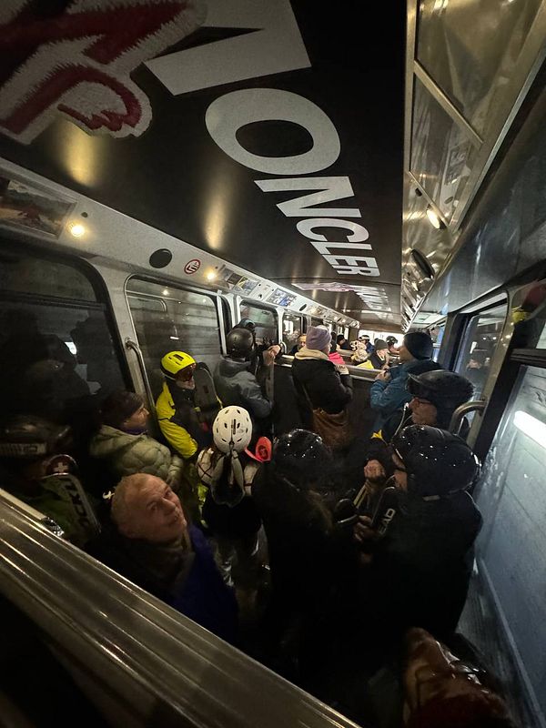 A crowded ski gondola filled with people wearing winter sports gear.