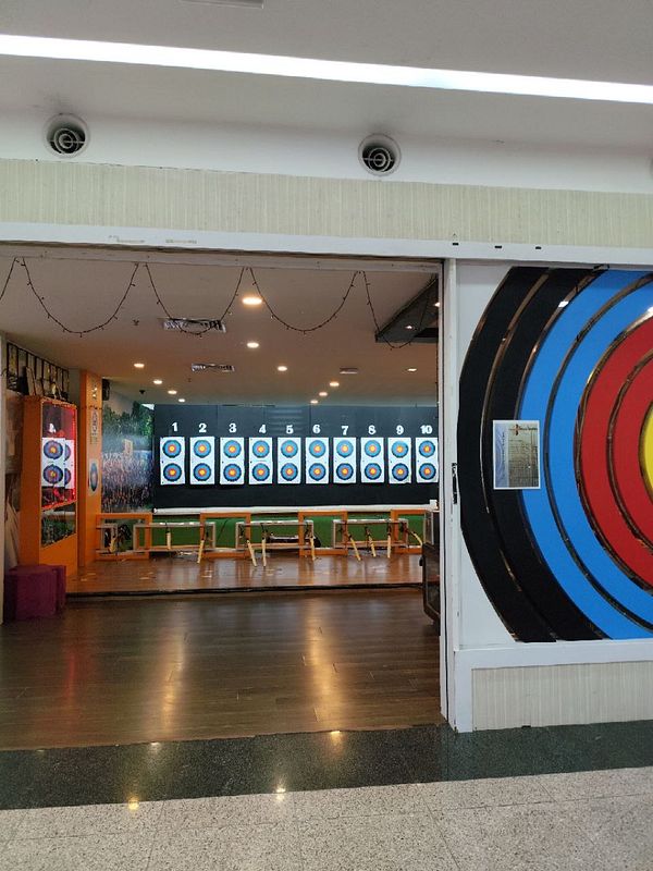 A group of friends practicing archery outdoors with colorful targets set up on stands.