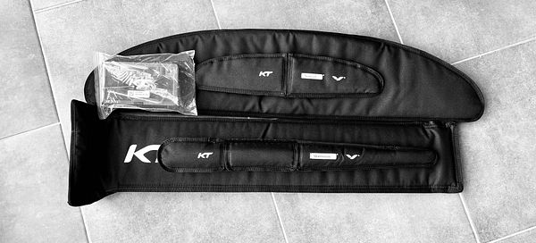 A black wing foil set from the KT Team is displayed on a tiled surface.