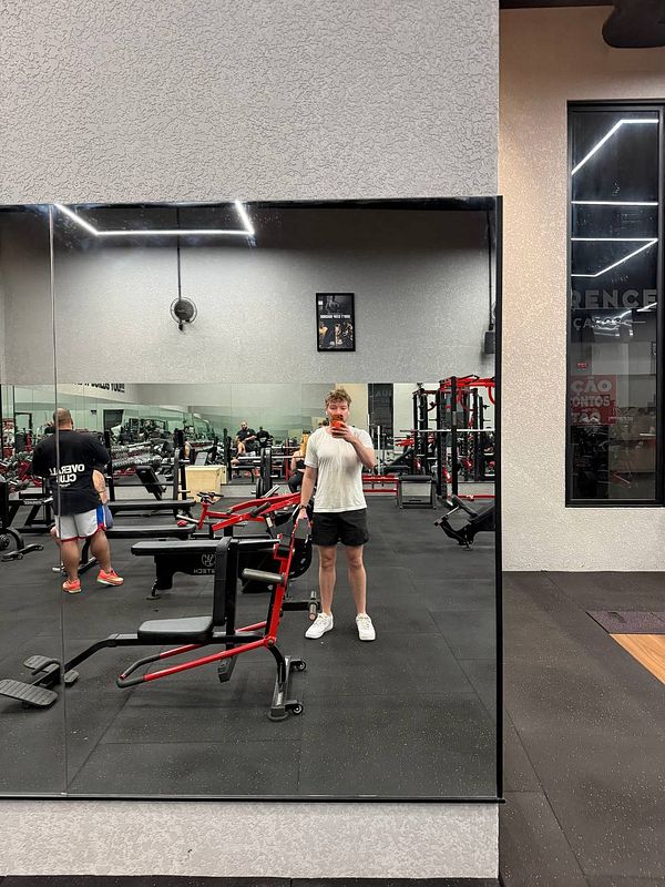 Photograph of a gym with multiple treadmills and fitness equipment under bright ceiling lights.