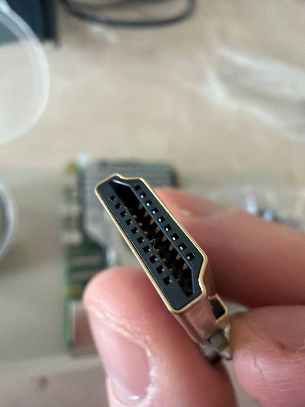 A close-up view of an HDMI connector held in a person's hand.