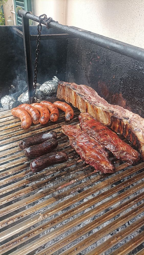 A barbecue grill filled with various types of meats being cooked.