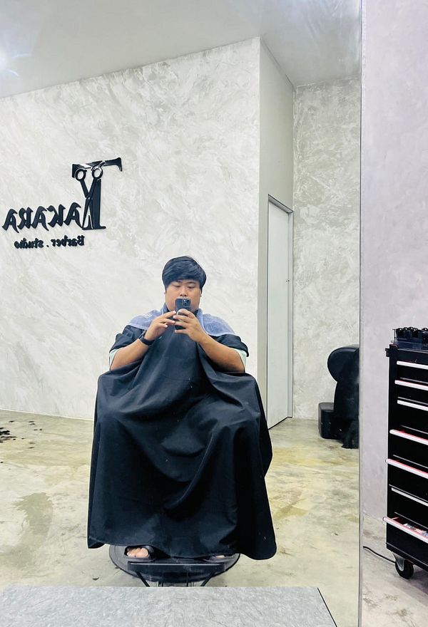 A person is seated in a salon chair, preparing for a haircut.