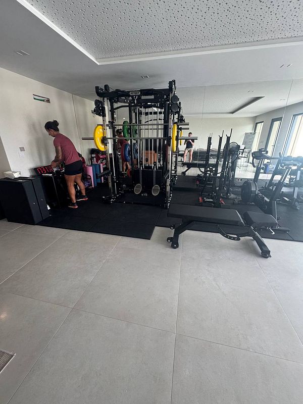A personal trainer is preparing equipment in a modern gym space.