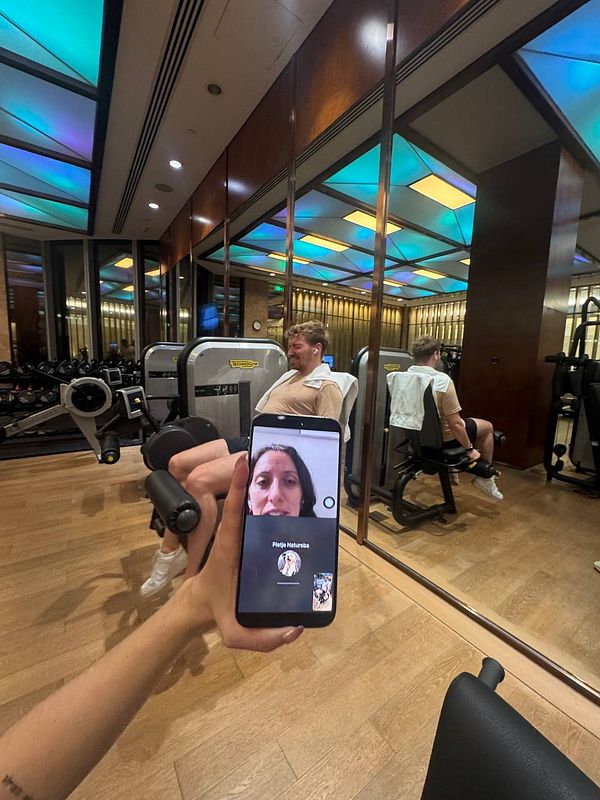 A person is video calling a trainer while working out in a gym.
